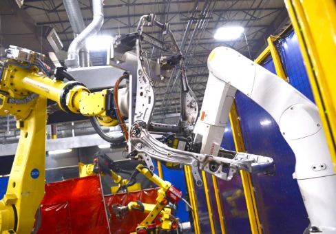 An industrial robot is lifting a seat frame.