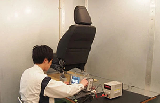 電磁環境から隔離されたシールドルームでシートの電装機能をテストしている社員