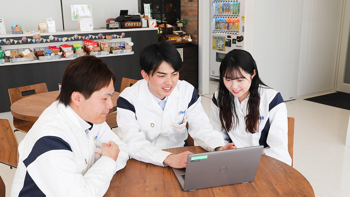 入社4年目社員3名が机を囲んで談笑する様子